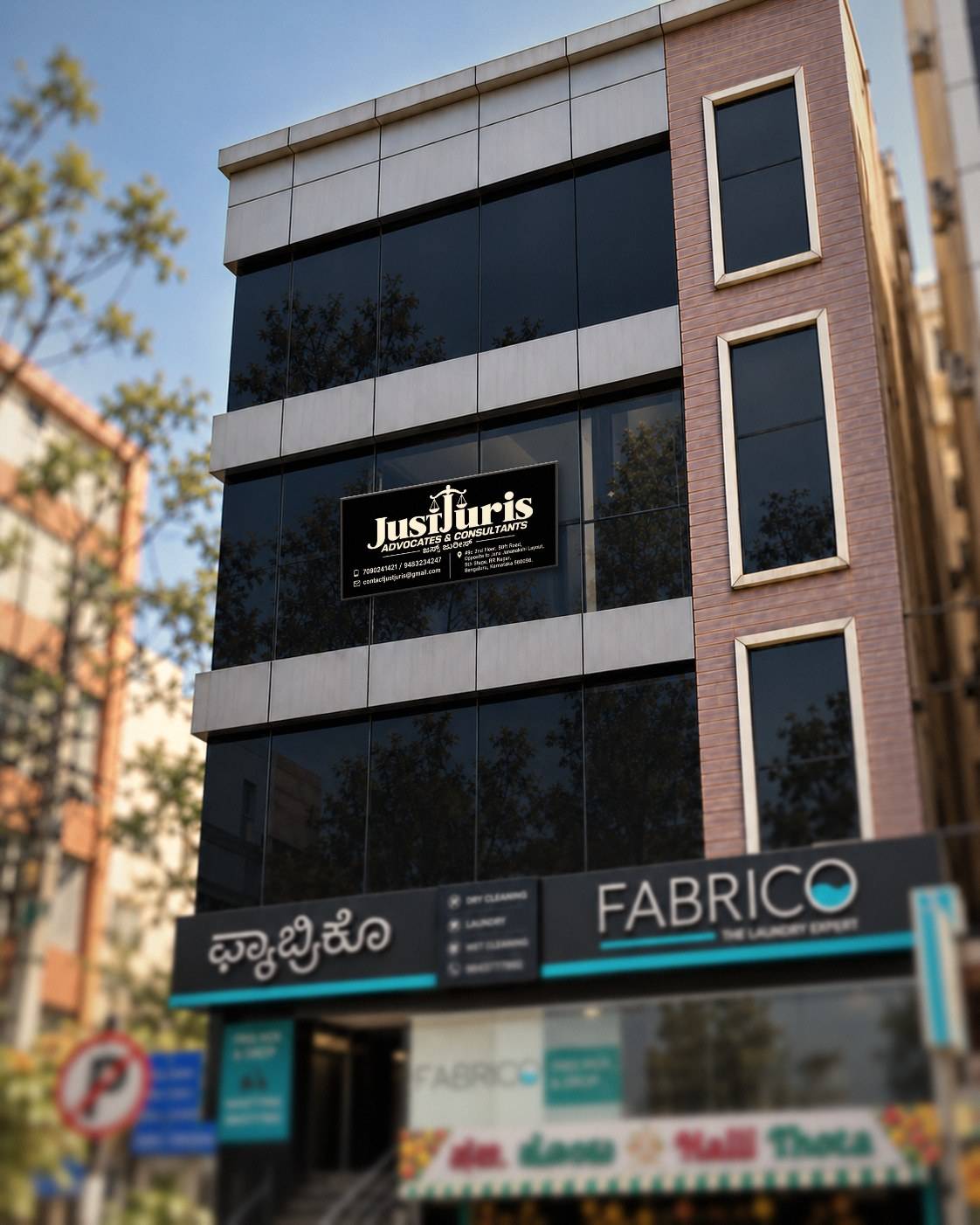 The JustJuris name board on the second floor of the office building in RR Nagar 5th Stage, above the Fabrico laundry